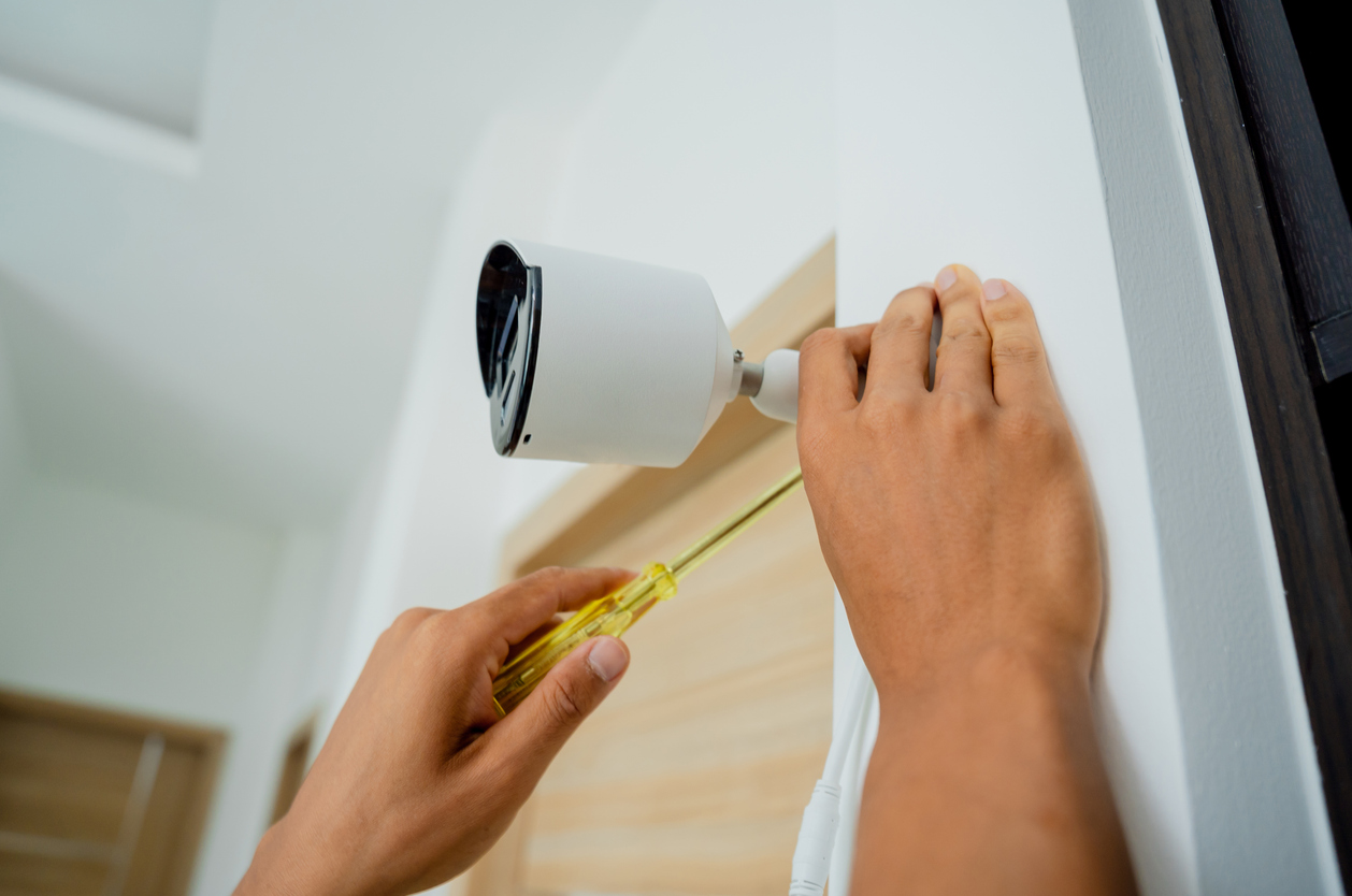 A technician installs a CCTV camera in a modern apartment.